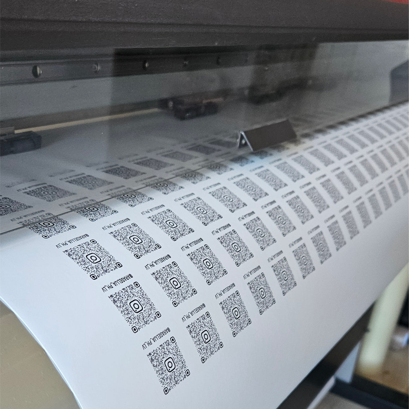 Sheet of paper with QR codes being printed by a printer.