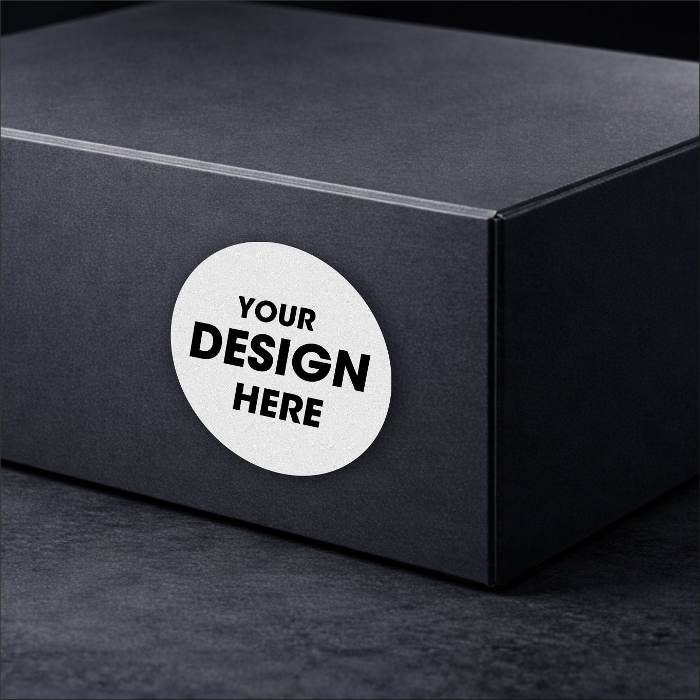 Black box with a round white sticker that says 'Your Design Here' on a dark background