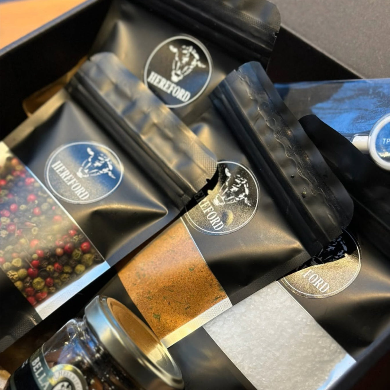 Black coffee bags with 'Hereford' branding on a wooden surface