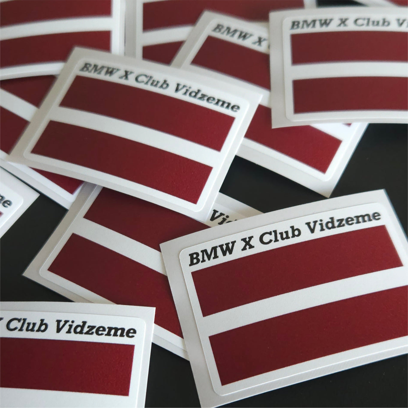 Stickers with 'BMW X Club Vidzeme' text on a dark background
