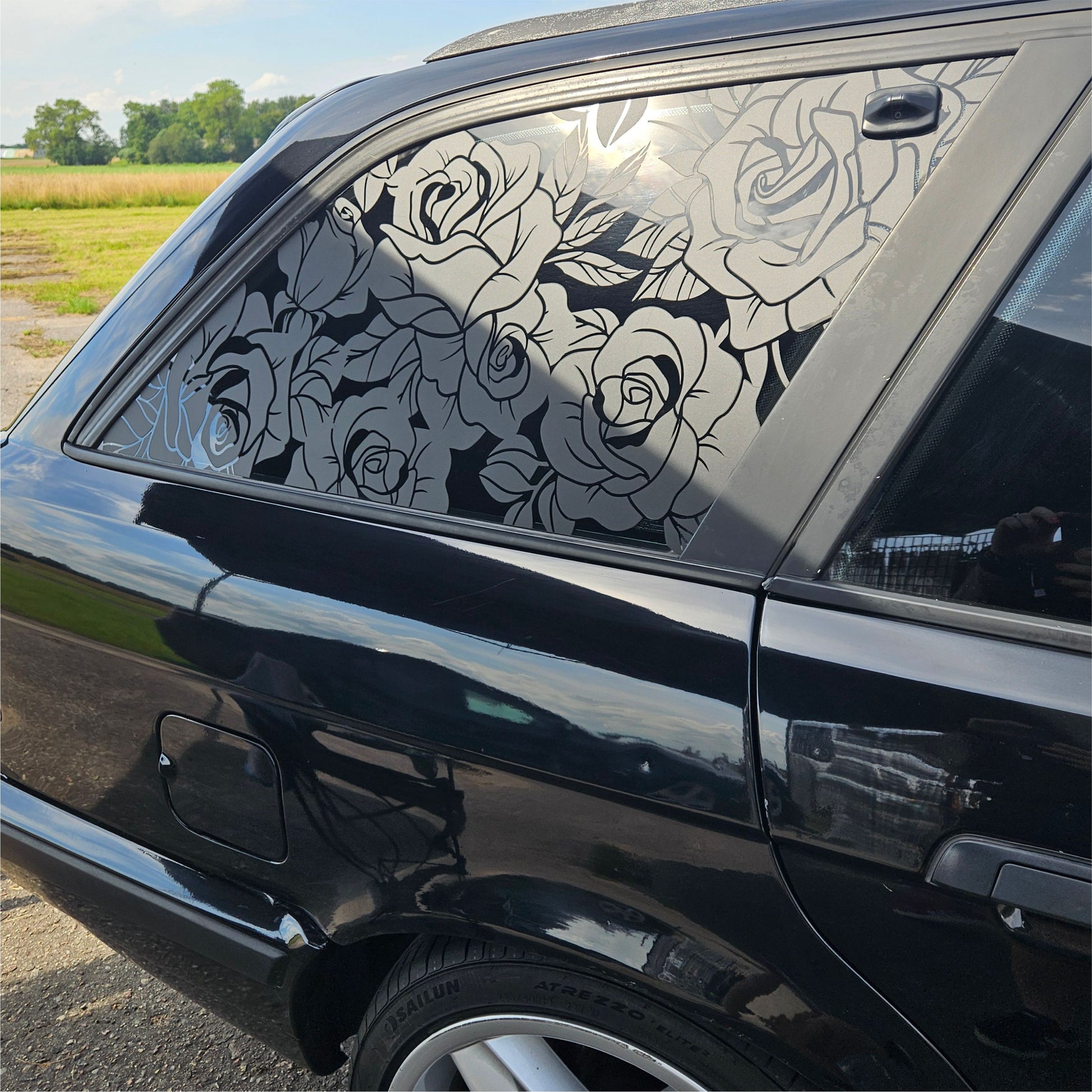Black car with rose patterned window decal outdoors