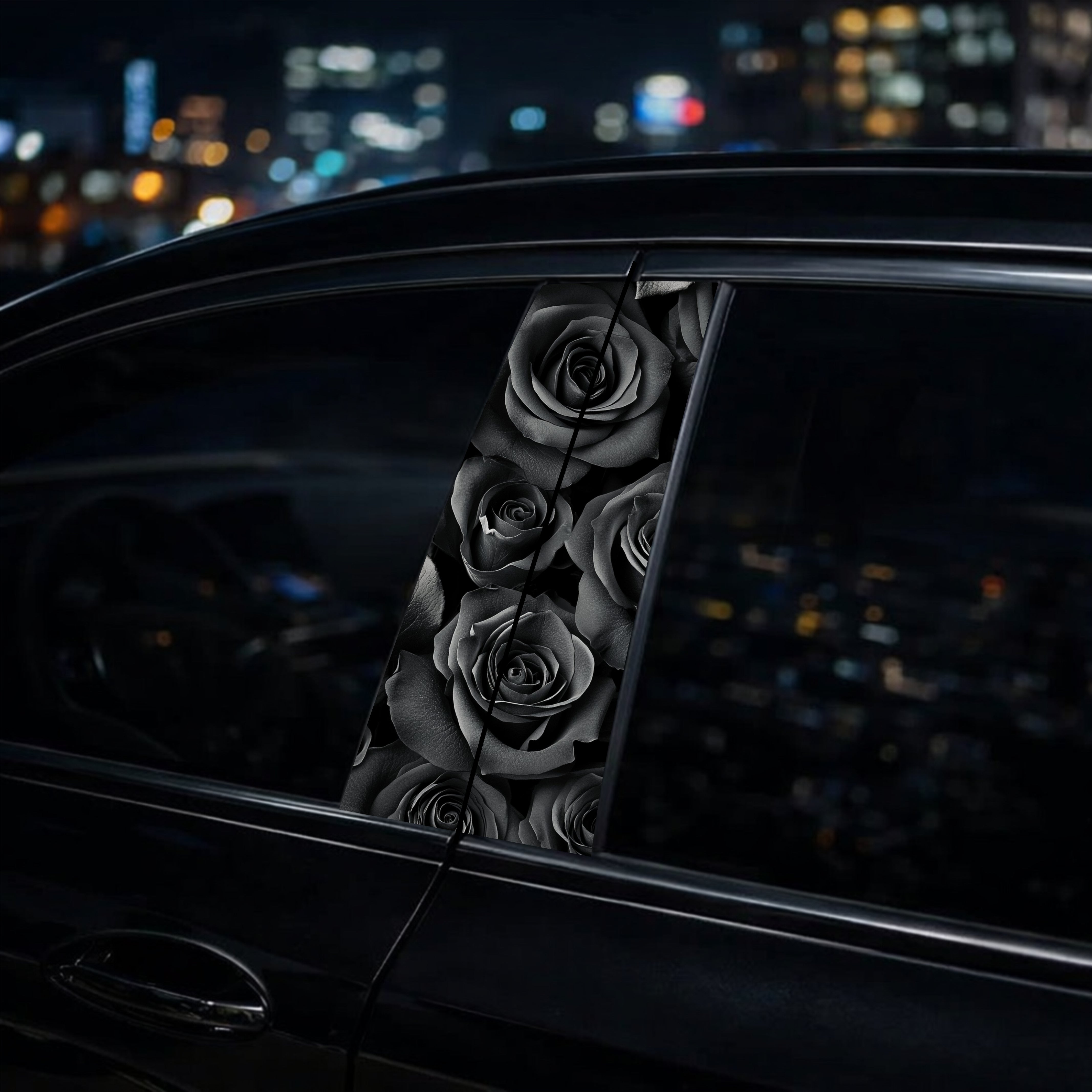 Decorative black roses on a car window with a cityscape at night.